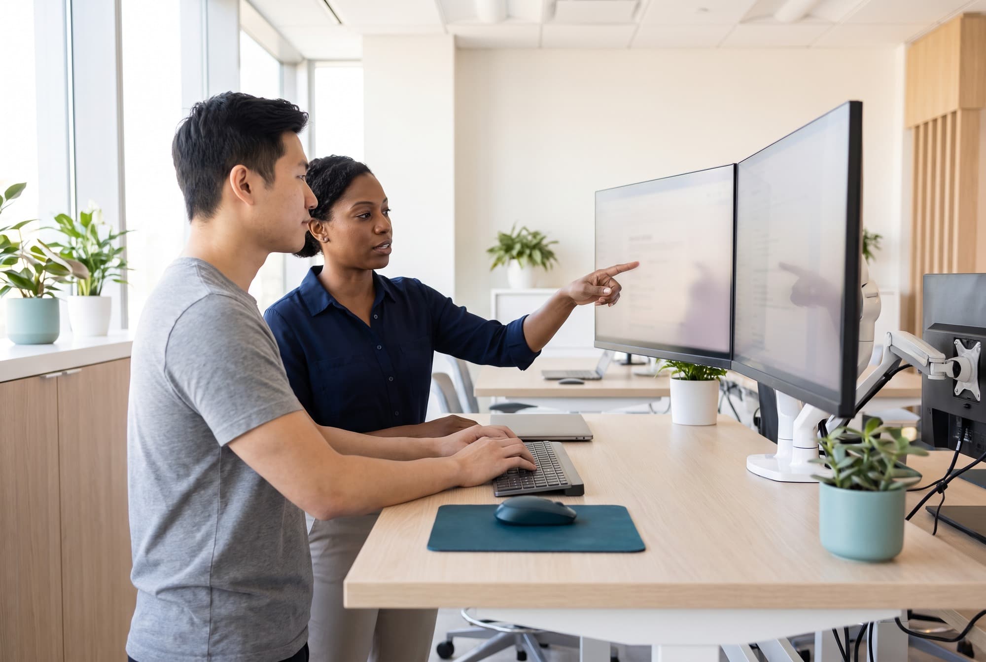 Two software developers working together at a standing desk