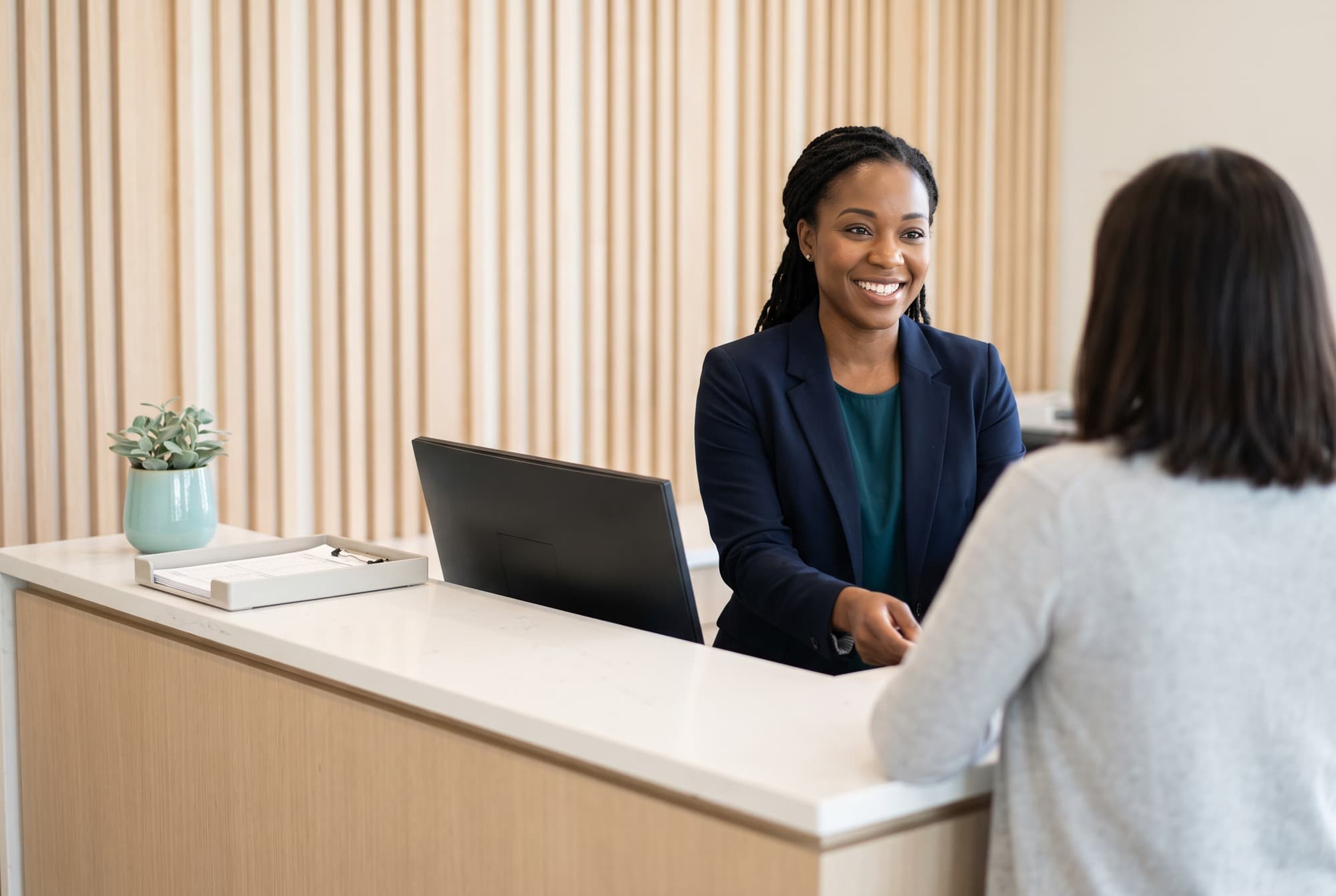 A receptionist helping a patient at the front desk of a modern practice